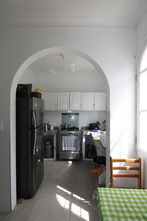 Shared kitchen with an arched doorway, fridge, gas stove and dining table