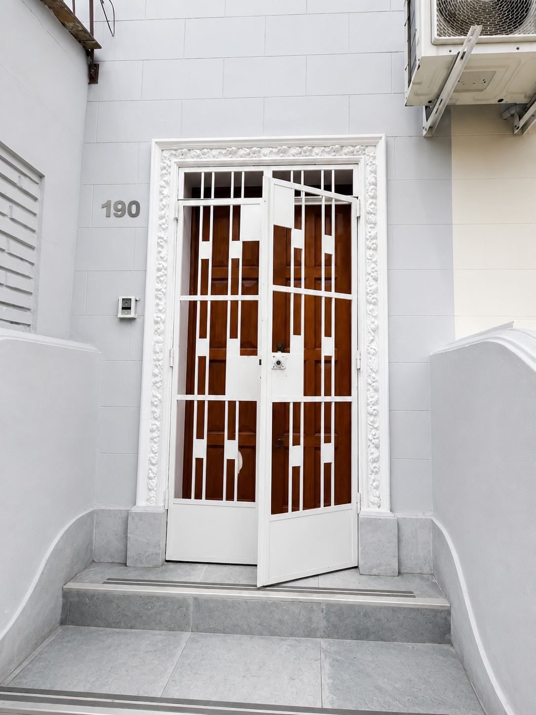 Puerta de entrada de Casa Águila y Cóndor, de madera con reja blanca y el número 190 en la fachada