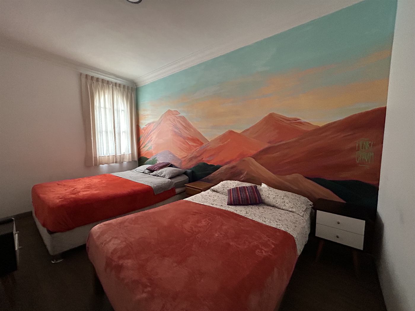 Habitación familiar con baño privado y mural pintado a mano de montañas andinas al atardecer