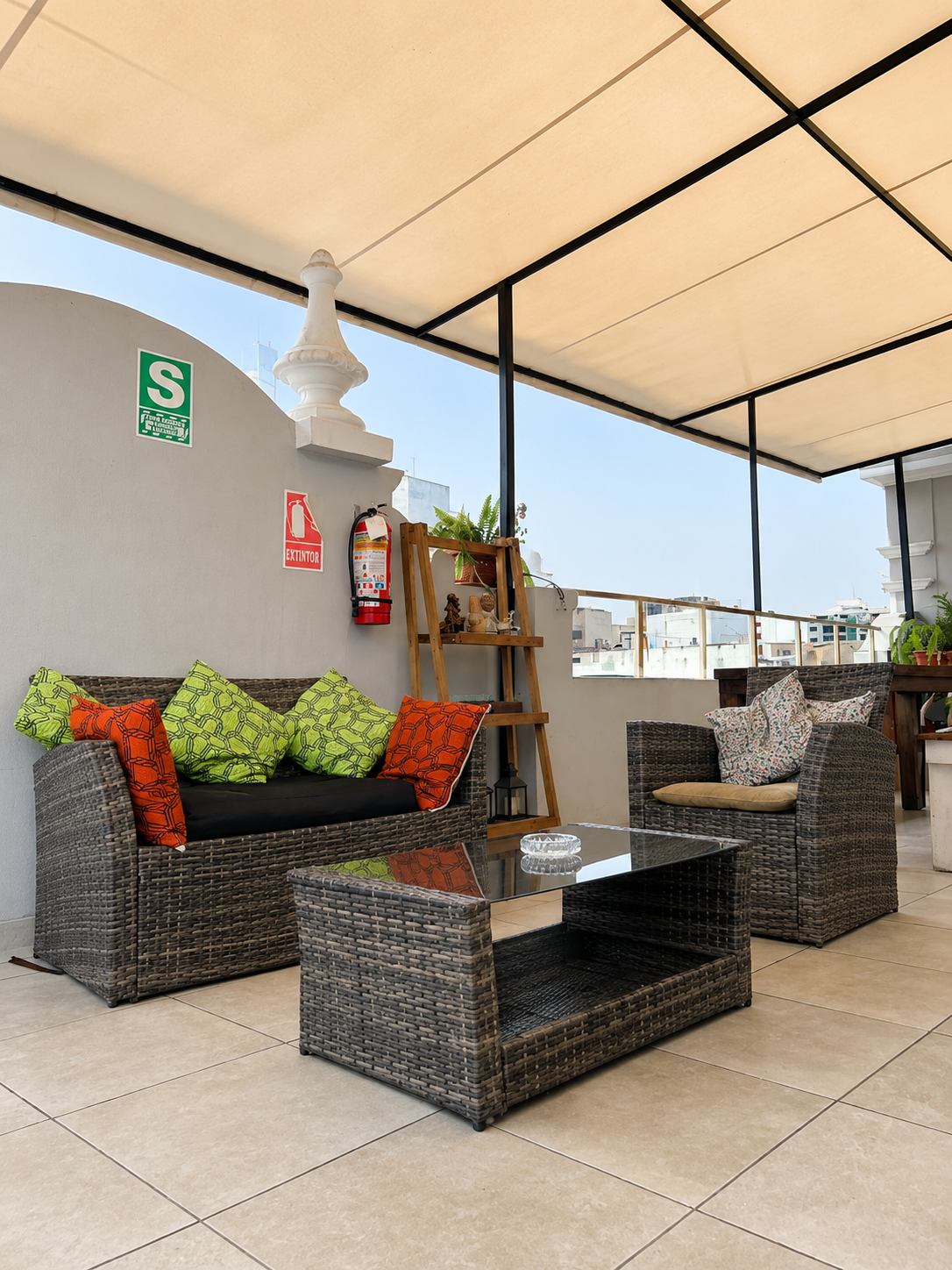 Terraza techada con sillones, mesa larga de madera y plantas, en Casa Águila y Cóndor